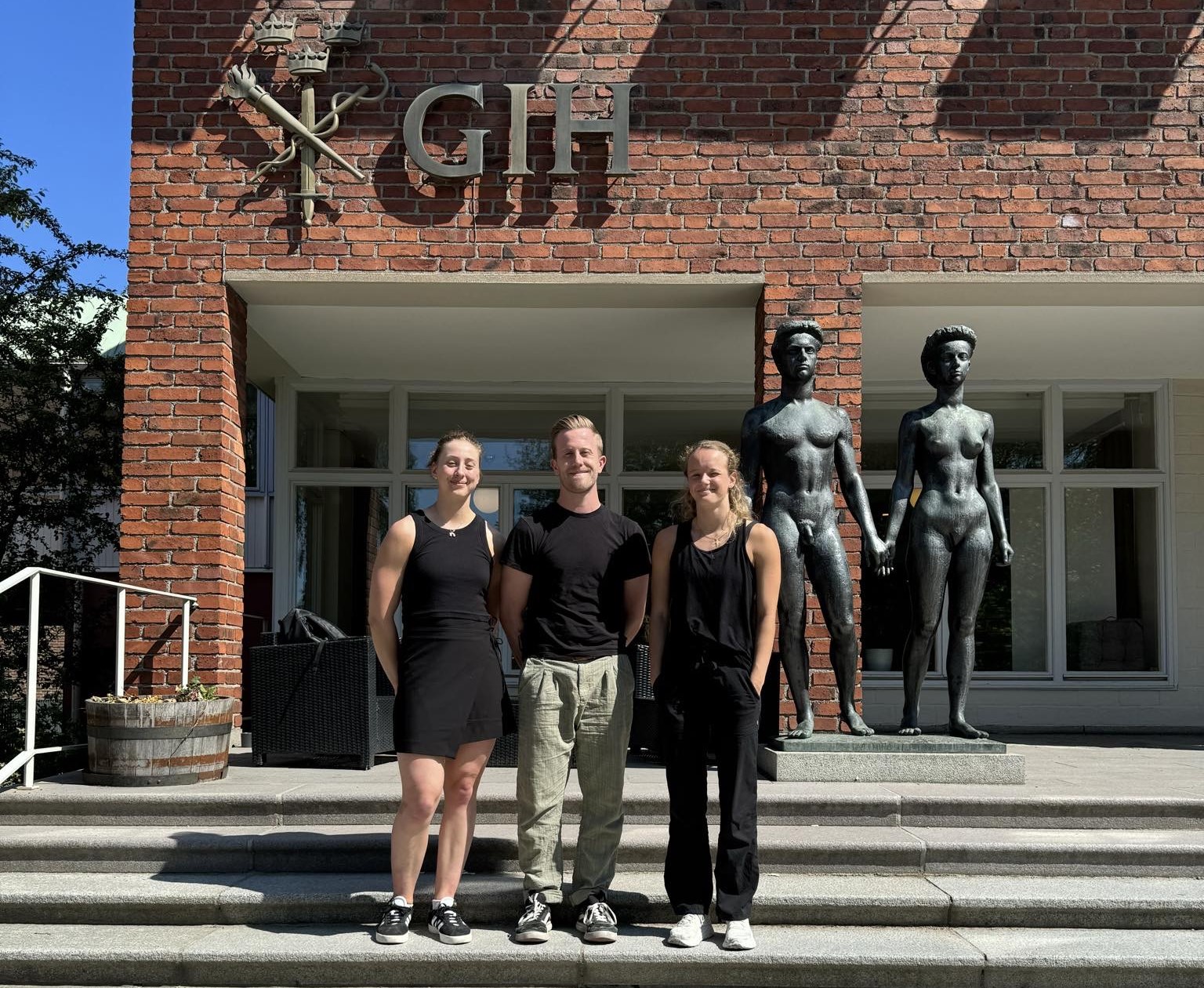 Tre studenter står framför ingången till Gymnastik- och Idrottshögskolan i Stockholm. 