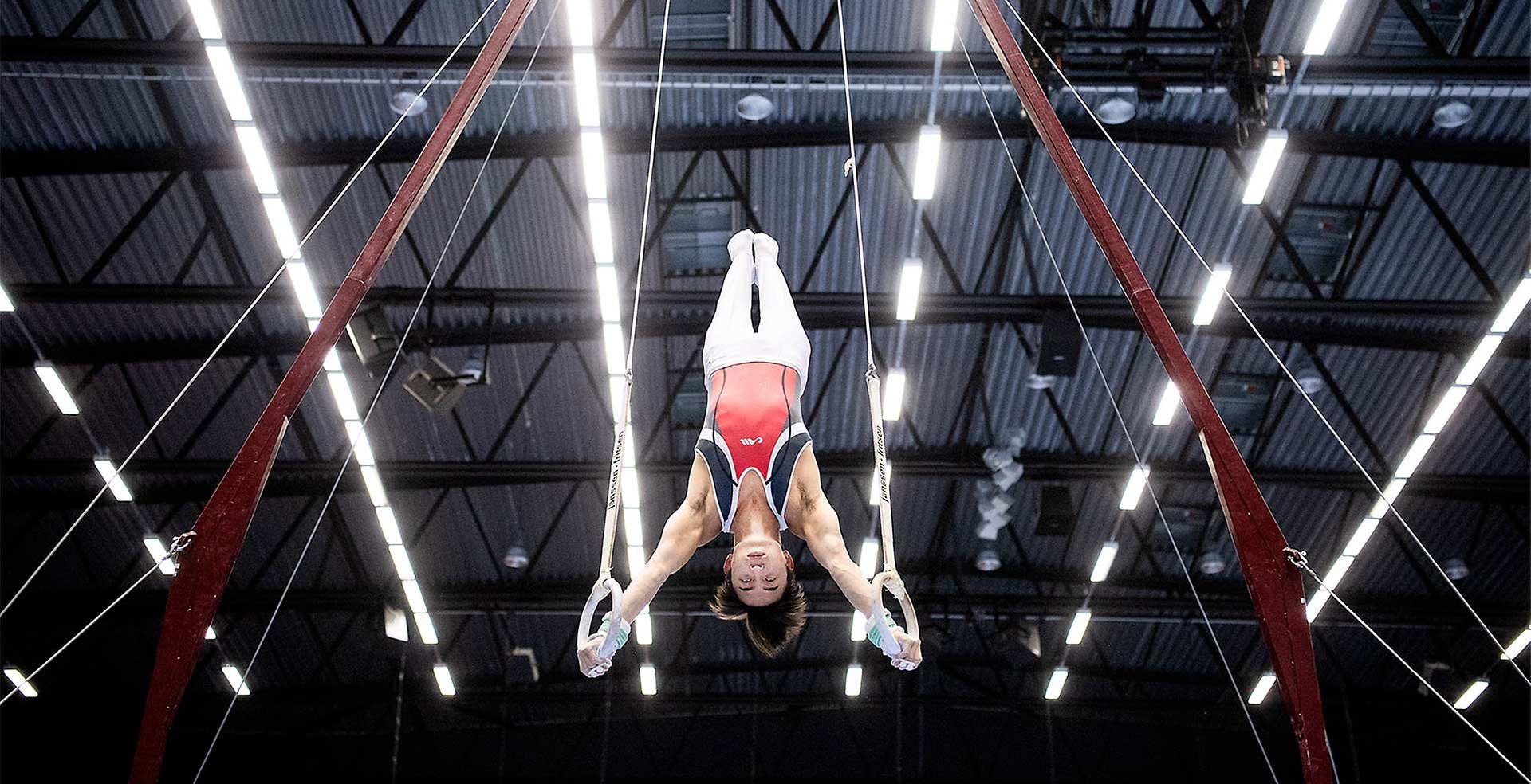 Man utför artistisk gymnastik i ringar.